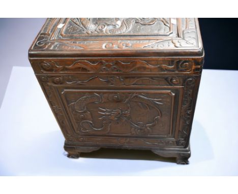 An early 20th Century hardwood camphor chest, carved with Chinese dragon detail to top and all sides, stands on dragon detail