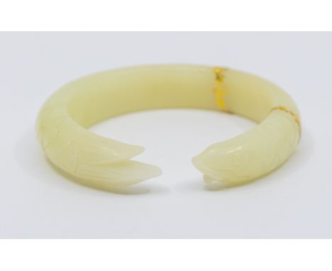 A carved nephrite jade torque bangle, carved in the form of a fish, with overlaid gilt decoration, width approx 13mm, total g