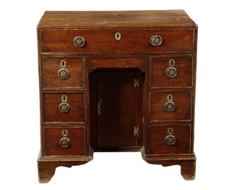 A George II mahogany kneehole desk, with a caddy moulded edge top above a frieze drawer and seven further drawers around a ce