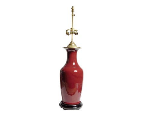 A Chinese porcelain sang de boeuf vase table lamp, with gilt brass mounts, with three lights and on an ebonised stand, fitted