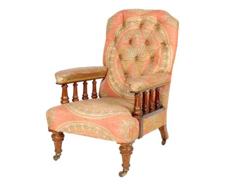 A late Victorian walnut easy armchair, with a button upholstered back with padded arms on fluted column supports, on tapering