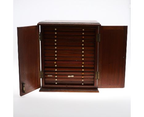 A Victorian Mahogany coin cabinet with a rectangular top with moulded edge above twin doors enclosing sixteen lined trays. Co