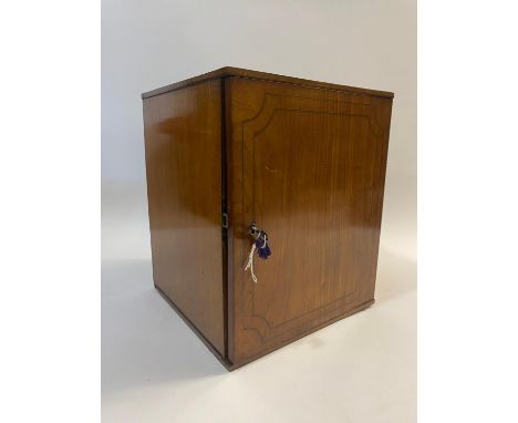 A single door coin cabinet with strung edges, the interior fitted with fourteen coin trays with 32mm shallow coin places, 30 