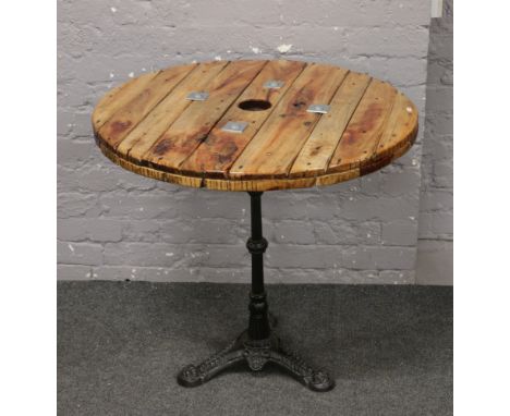 A pub table with cast iron tripod base and plank top.