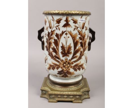 A ceramic twin handle vase with brass pedestal and liner.