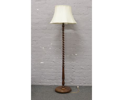 An oak barleytwist standard lamp with circular base and cream shade.