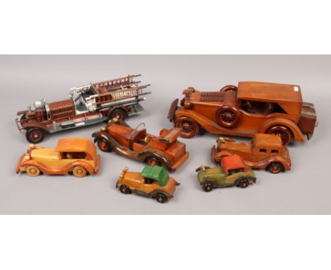 A painted metal medal of a vintage fire engine and six wooden models of vintage cars.