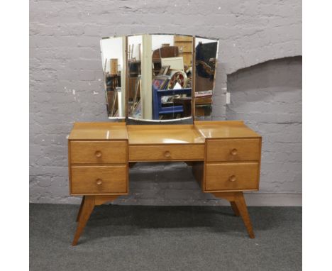 A light oak triple mirror dressing table raised over splayed legs.