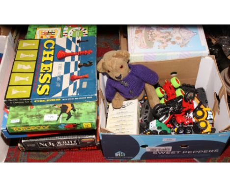 A collection of boxed board games, along with a box of model vehicles and vintage teddy bear.