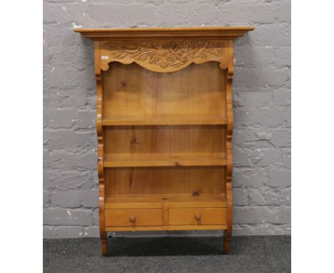 A carved pine three shelf wall hanging unit with two drawer base.