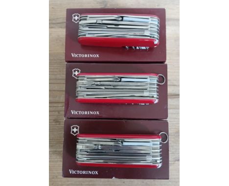 A group of three Victorinox Swiss Army SwissChamp multi-tool penknives with boxes.