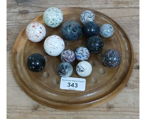 A solitaire board containing assorted glass marbles including blizzard designs etc, ranging in diameter from 24mm to 34mm.