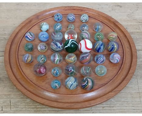 A solitaire board containing 37 glass marbles, various designs, ranging in diameter from approximately 16mm to 27mm.