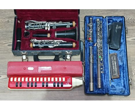 A group of four musical instruments comprising a clarinet, a flute, a Melodica and a mouth organ.