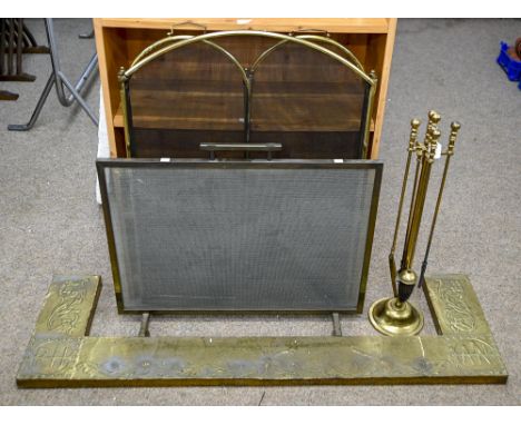 An Arts &amp; Crafts repousse brass fender, 140 x 43cm, a set of brass fire irons, a brass three-fold spark guard and another