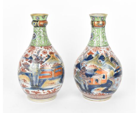 A pair of 19th century Imari porcelain vases, of bottle vase shape with knopped necks, the top applied with green enamel, the