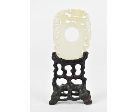 A Chinese carved and pierced white jade plaque on stand, designed with mythical creature and phoenix, with circular pierced c