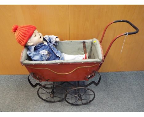 A childs doll with papier mache head, arms and legs, sleeping eyes and open mouth in a good quality vintage pram with metal c
