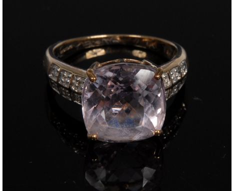 A Kunzite and diamond ring, central cushion kunzite, 6.58ct, flanked by twelve diamond accents six to each shoulder, total di
