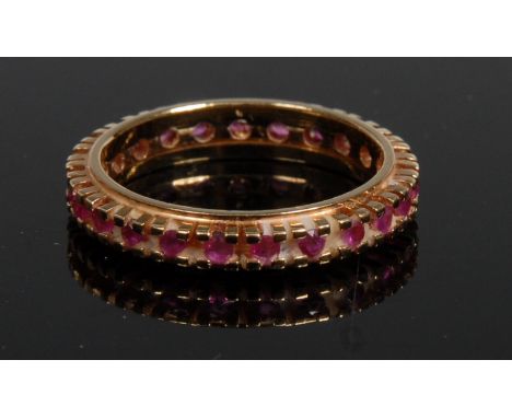 A ruby eternity ring, encrusted with a continuous band of small pink ruby's, 18ct gold shank, size L, 3.2g gross