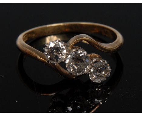 An Edwardian diamond crossover trilogy ring, central round brilliant cut diamond, flanked by smaller conforming diamonds, tot