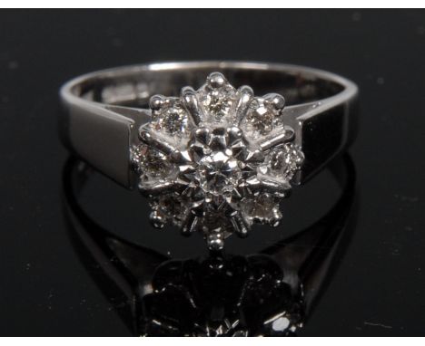A nine stone diamond flower head cluster ring, illusion set to an 18ct white gold crown and shank, size M 1/2, 4.7g gross