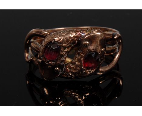 A garnet set double snake ring, intertwined snake heads each set with a single oval garnet, 9ct rose gold shank, size W, 5.4g