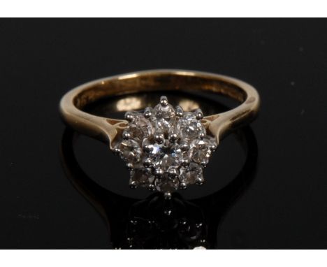 A nine stone diamond cluster ring, central raised round brilliant cut diamond, surrounded by a band of eight conforming diamo