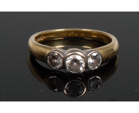 A three stone diamond ring, central round brilliant cut diamond raised above two smaller conforming diamond set shoulders, 18