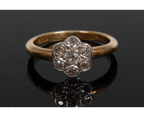 A seven stone diamond flowerhead cluster ring, central round brilliant cut diamond, surrounded by a band of six conforming di