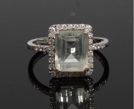 A diamond and pale blue aquamarine ring, central baguette cut aquamarine surrounded by a band of twenty six diamond accents, 