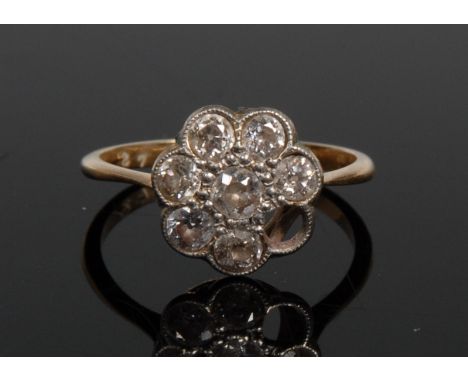 An eight stone diamond flowerhead cluster ring, central round brilliant cut diamond, flanked by a band of seven conforming st