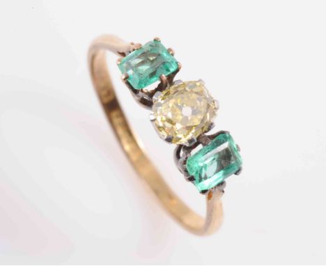 AN EMERALD AND DIAMOND RING, the oval mixed cut yellow coloured diamond eight claw set between two rectangular mixed cut emer