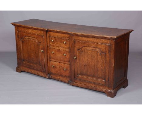 A GEORGE III OAK DRESSER BASE, with inverted breakfront, fitted with a pair of ogee arch panel doors flanking three graduated