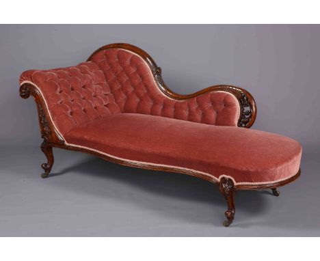 A VICTORIAN WALNUT BUTTON BACK CHAISE LONGUE, with scroll back and serpentine seat rail, raised on foliate capped short cabri