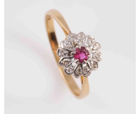 A DIAMOND AND RUBY RING, the round cut ruby six claw set raised within a surround of twelve brilliant cut diamond highlights 