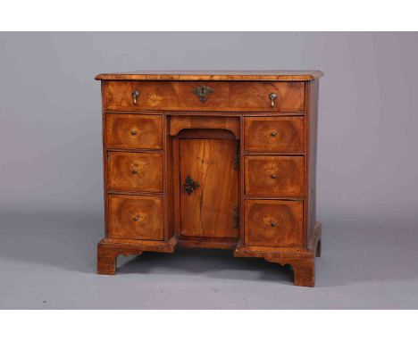 AN EARLY 18TH CENTURY OYSTER VENEERED WALNUT KNEEHOLE DESK, the quarter veneered, cross banded and moulded top above a recess