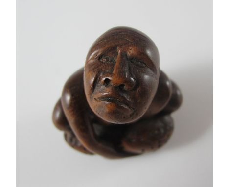 Netsuke. Mann hebt einen Stein. Holz. Himotoshi im Rücken. Mitte 19. Jh. H 4,2 cm