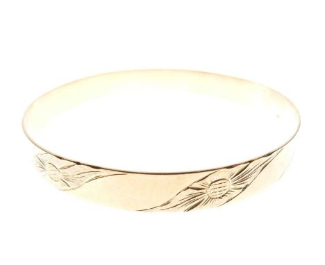Yellow metal bangle stamped 750, externally engraved with diagonal bands of flowerheads alternating with plain panels, 60mm i