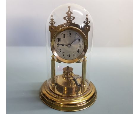 A brass anniversary mantle clock under glass dome.