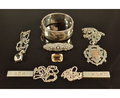 A silver bangle with engraved decoration, a silver fob with applied gold detail, silver watch, two silver ingots, silver pend