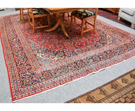 Kashan Carpet, the blood red field of palmettes and vines centred by a pole medallion, framed by spandrels and indigo borders