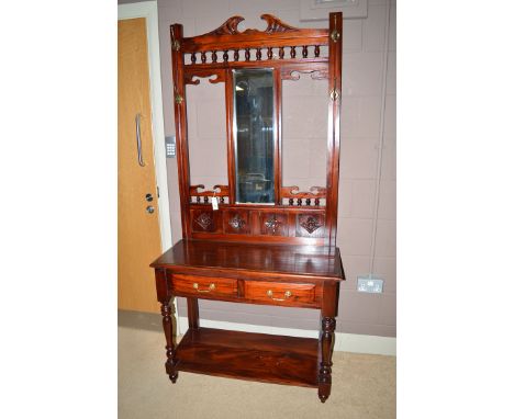 A 20th Century stained wood hall stand, the carved cresting rail above spindles and bevelled lower panel flanked by brass han