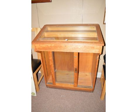 A second half 19th Century oak shop display cabinet, the glazed angled top enclosing three tier display area, above glazed pa