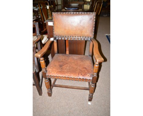 A single early 20th Century oak carver chair, the back and seat panel upholstered in tan leather with studded edges and raise