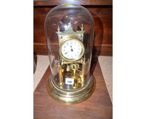 A perpetual motion clock, the brass movement with white enamel arabic dial, on turned uprights and circular base, under a gla