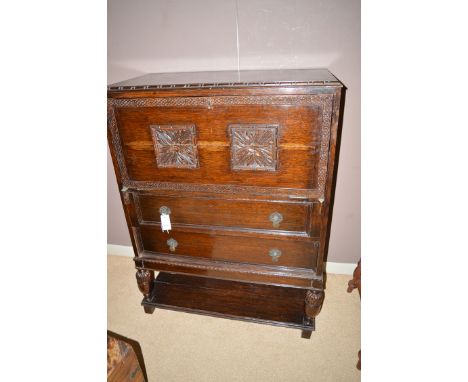 A mid 20th Century oak bureau, the rectangular top with moulded edge above floral panel fall-flap enclosing pigeon holes and 