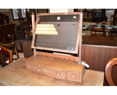 An early 19th Century mahogany toilet mirror, the rectangular mirror plate raised on reeded supports, the bowfront base fitte