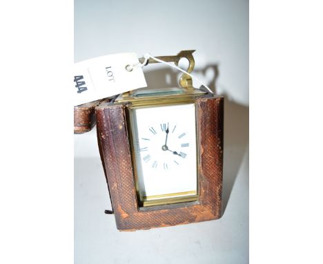A carriage clock in brass case with bevelled glass panels, white enamel roman dial, visible escapement and striking mechanism