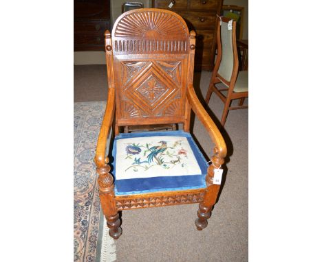 A 19th Century carved and stained oak occasional chair, the solid arched back with decorative carving above shaped arms, the 